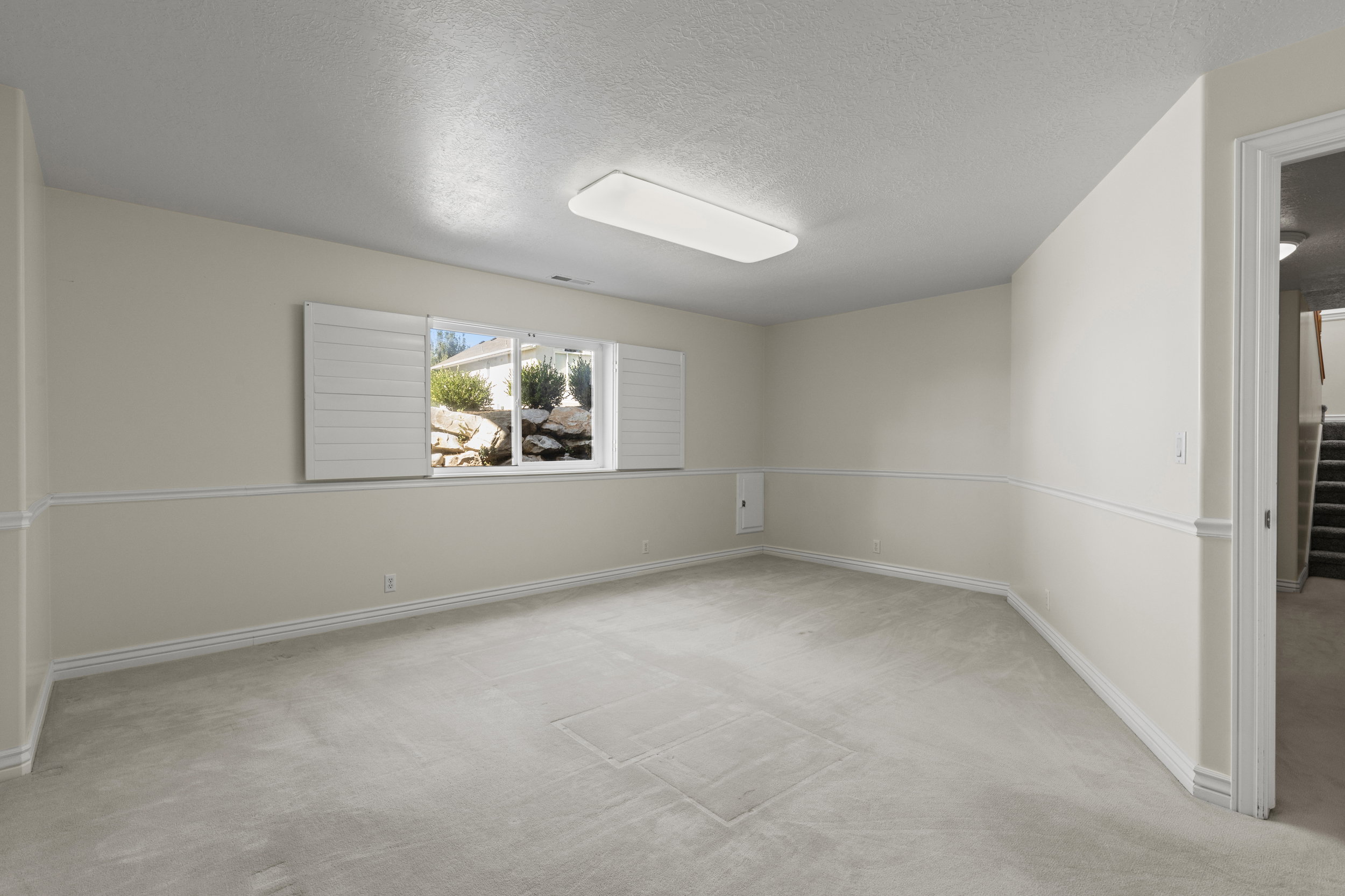 Empty room with light carpet and a textured ceiling