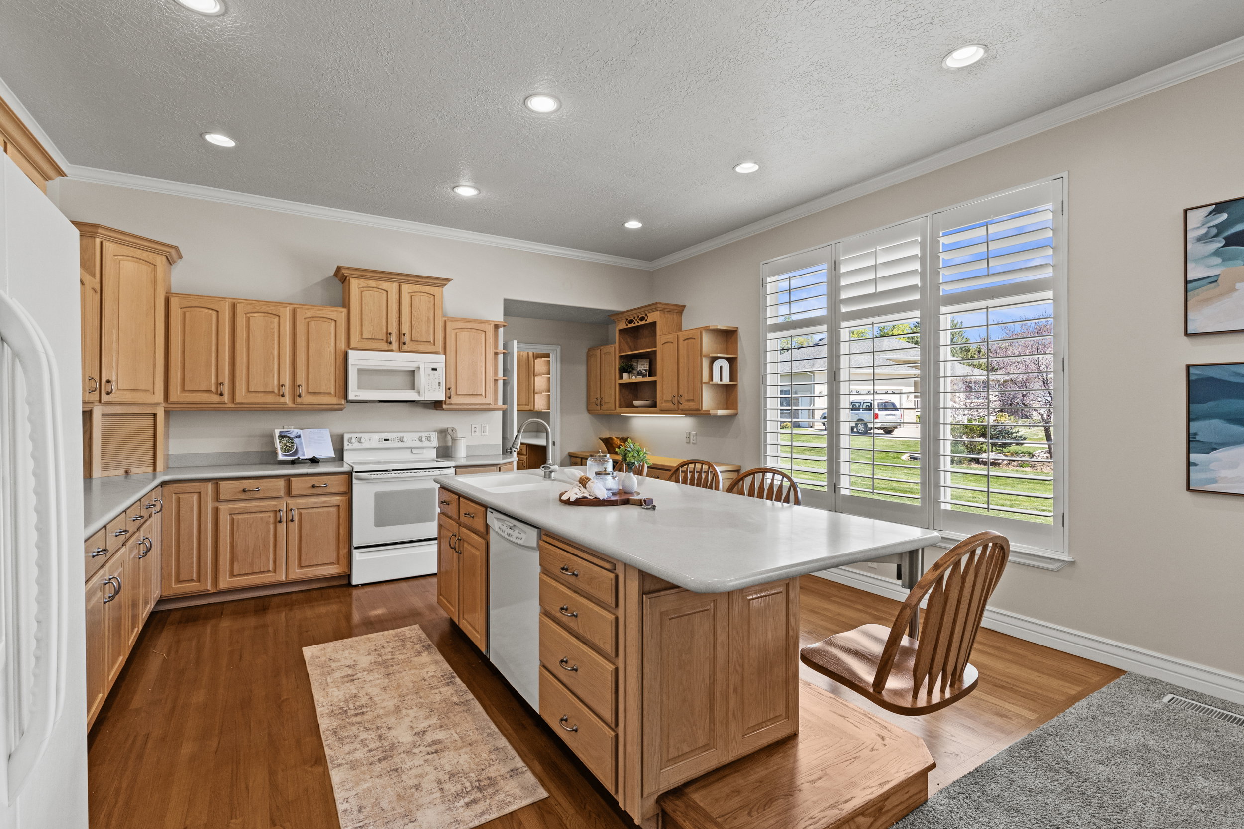 Kitchen with open shelves, light countertops, a center island with sink, white appliances, and dark wood finished floors