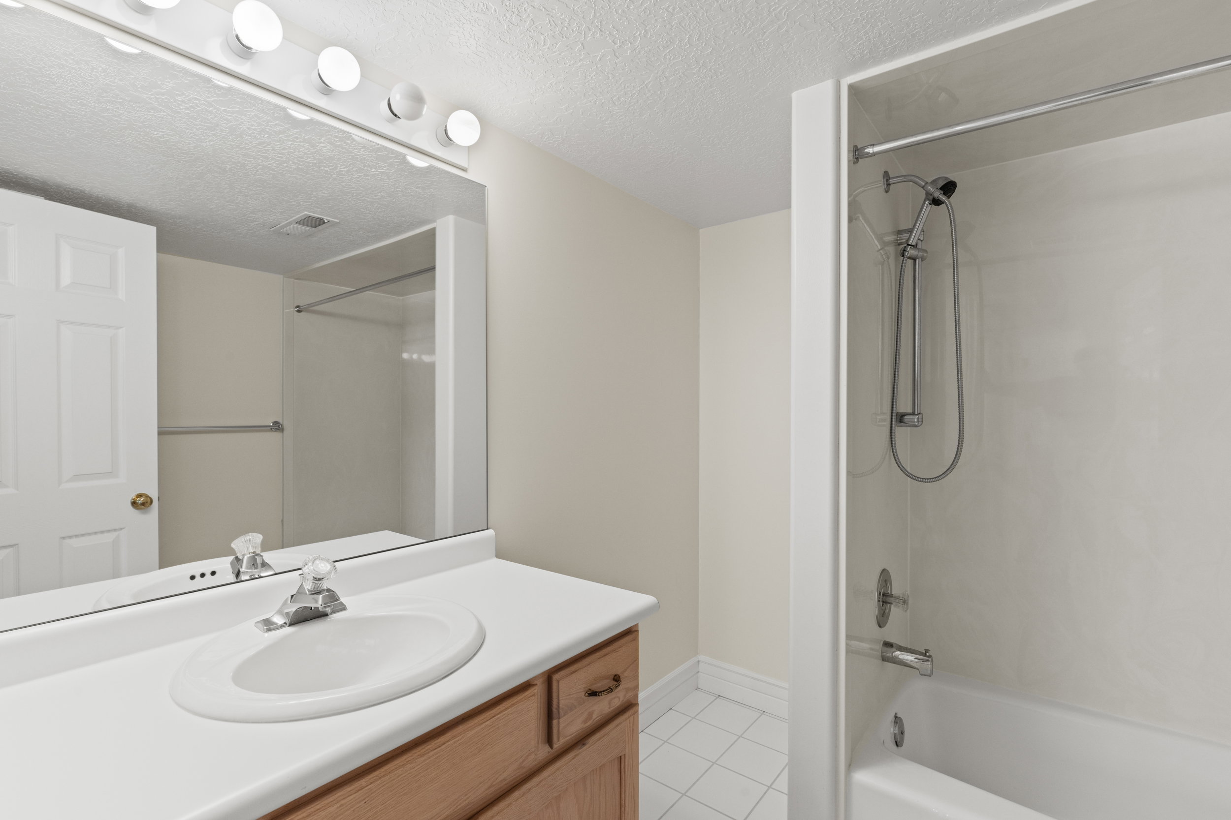 Full bath with vanity, a textured ceiling, tub / shower combination, and light tile patterned flooring