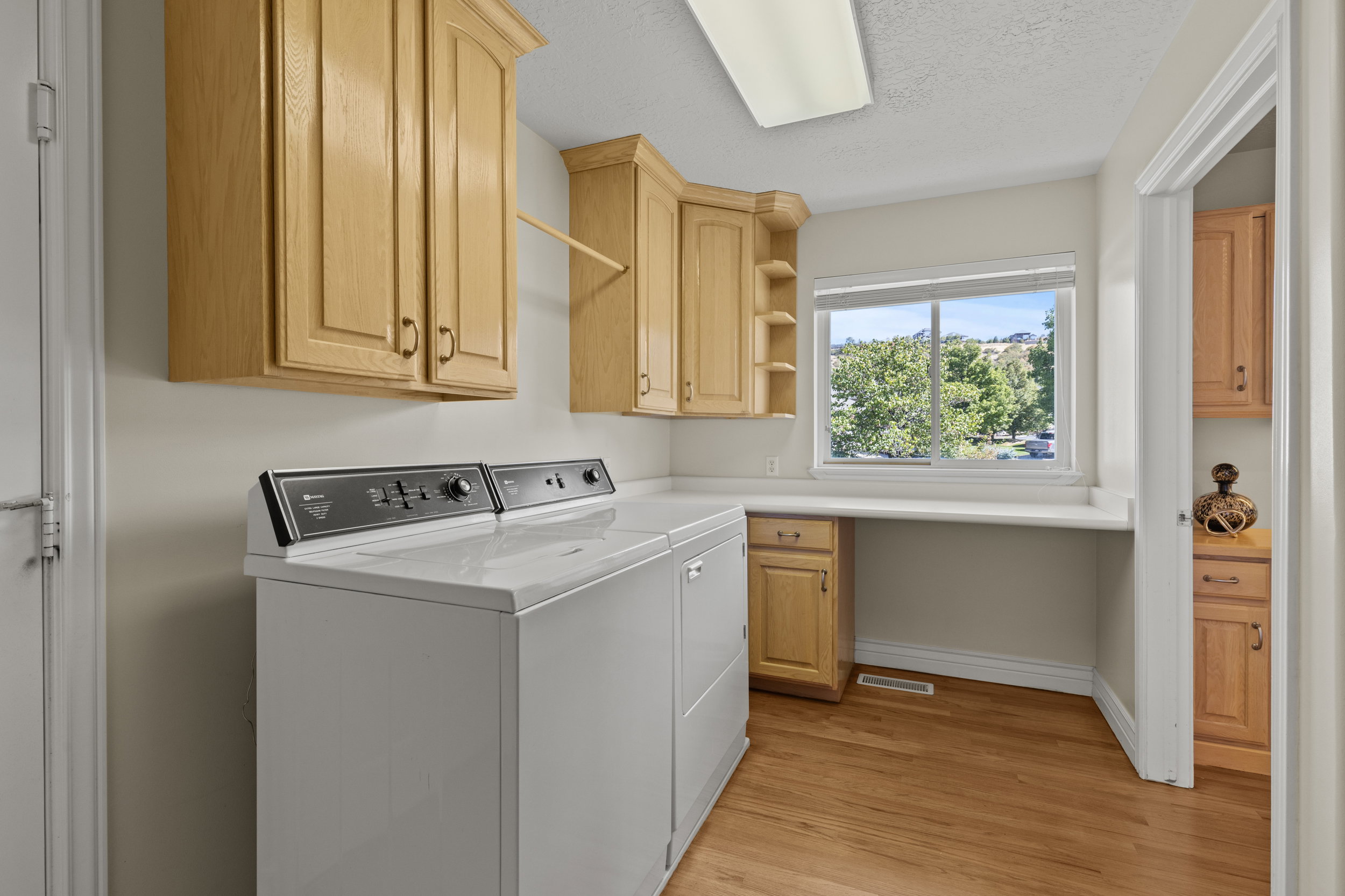 Laundry room with separate washer and dryer, light wood-style floors, a textured ceiling, and cabinet space