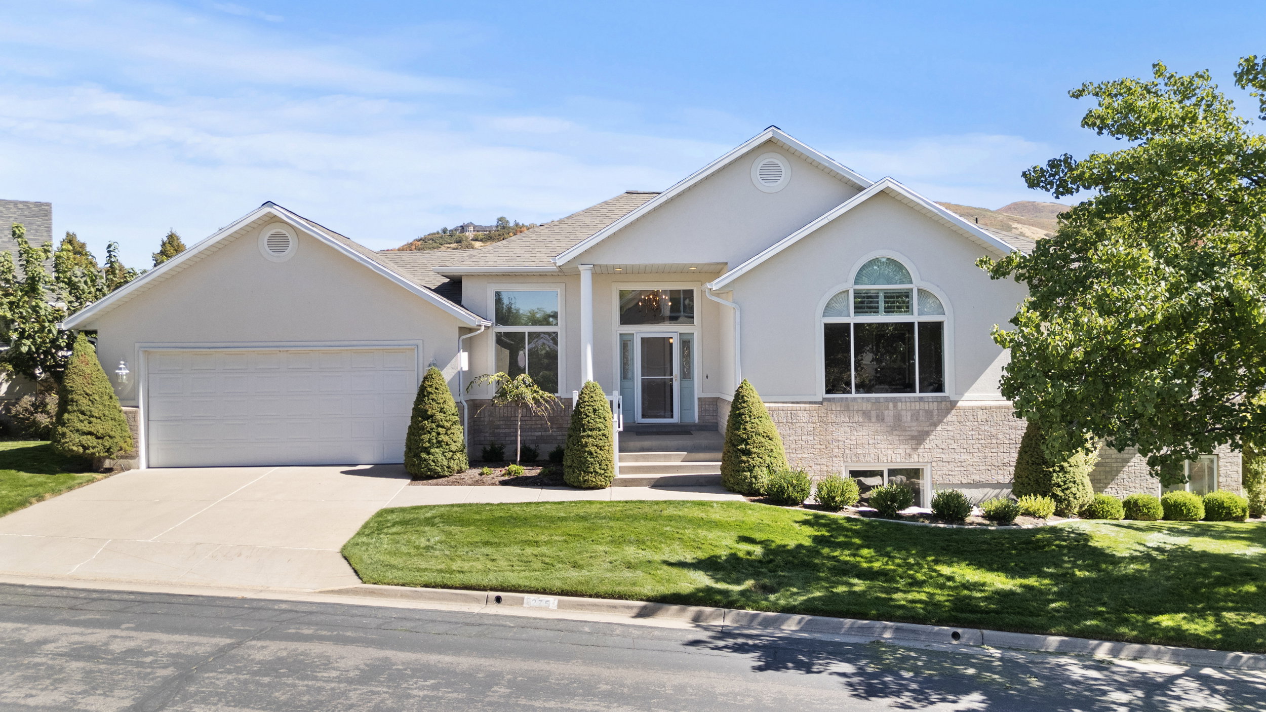Ranch-style home with stucco siding, an attached garage, concrete driveway, and a front yard