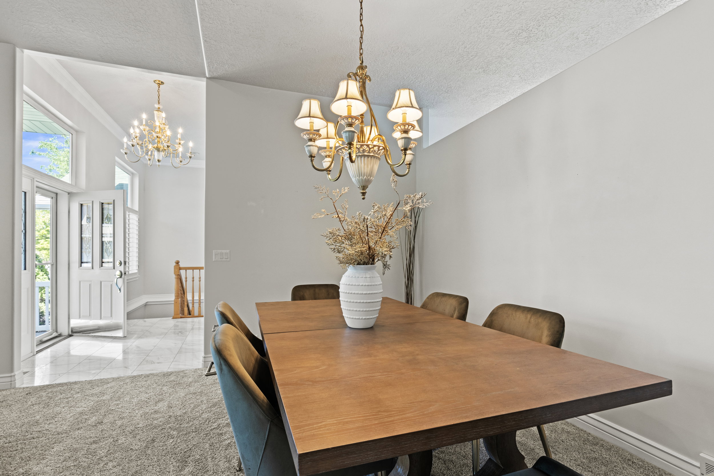 Dining room with a high textured ceiling, a chandelier, and light carpet
