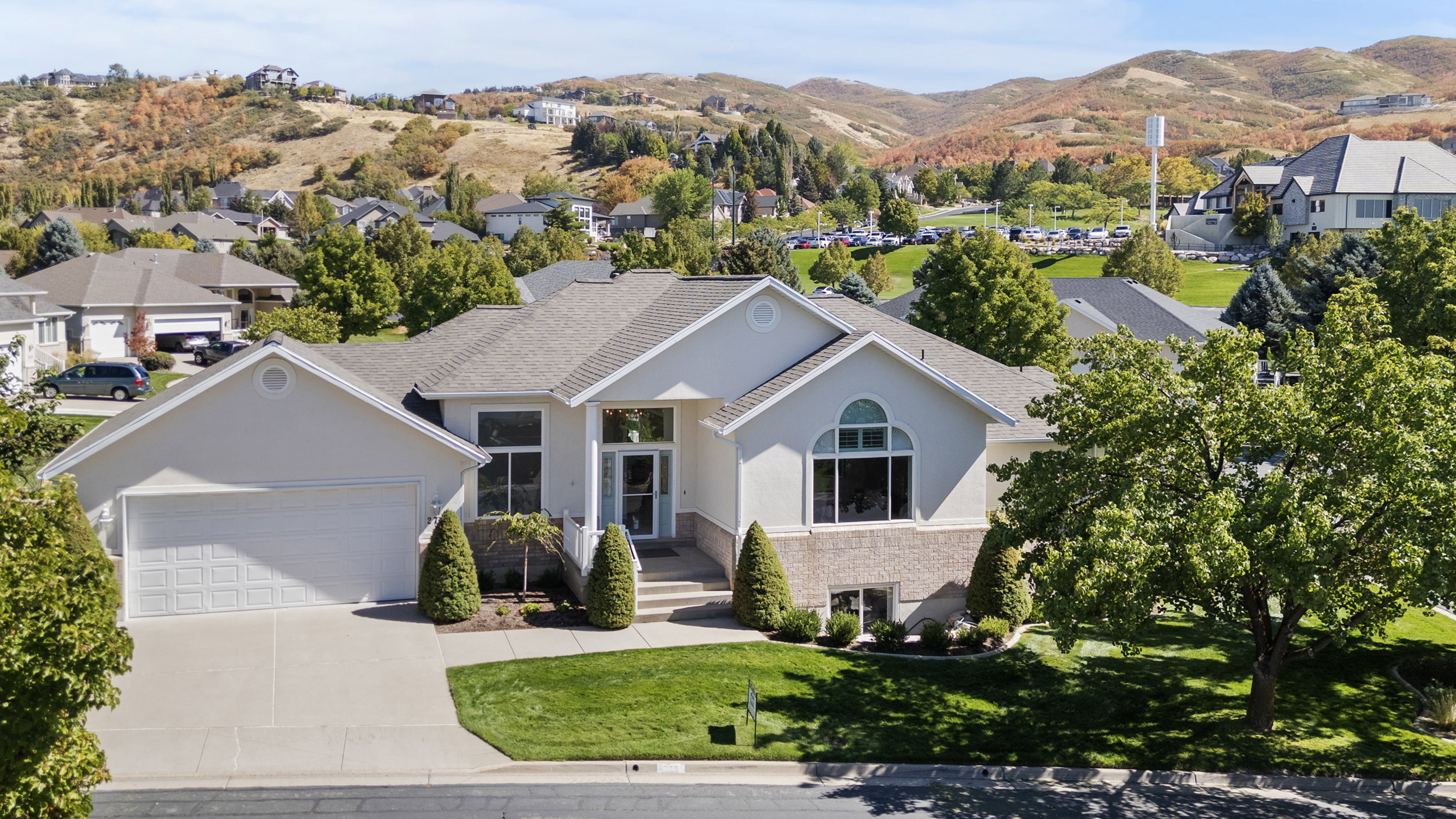 Ranch-style home with stucco siding, a garage, driveway, a front yard, and a mountain view