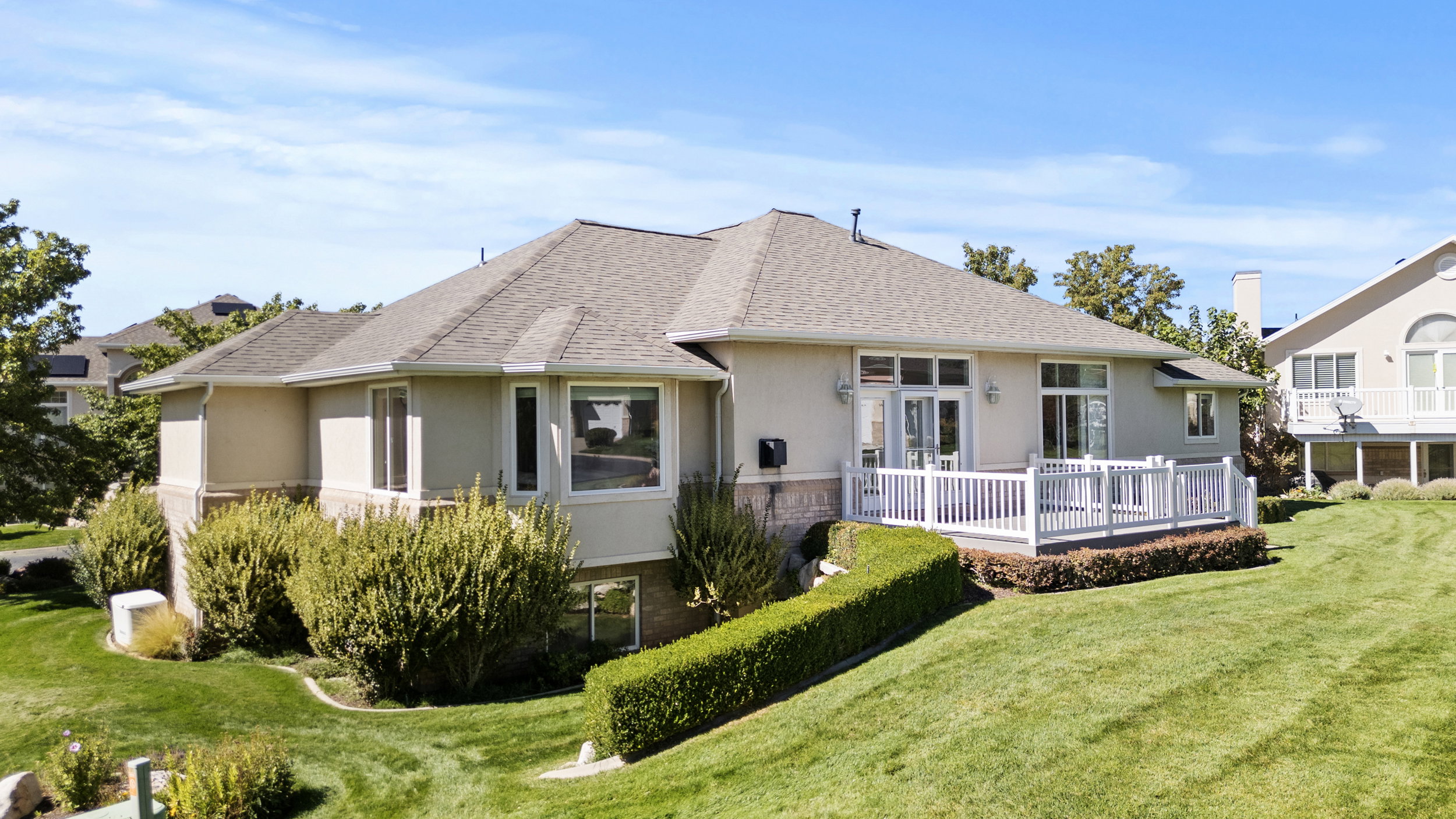 Rear view of property with a lawn, stucco siding, and a shingled roof
