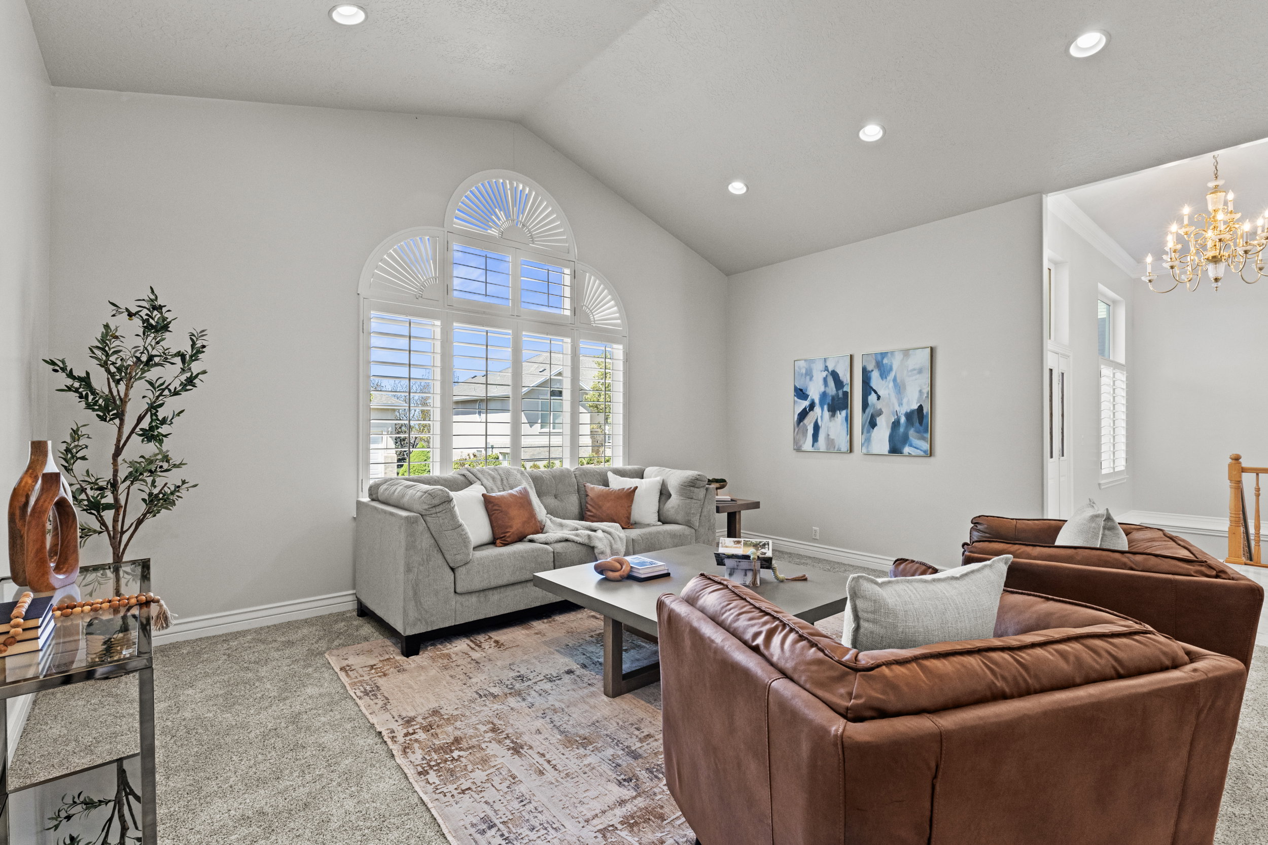Living room featuring light carpet, a chandelier, and a high ceiling