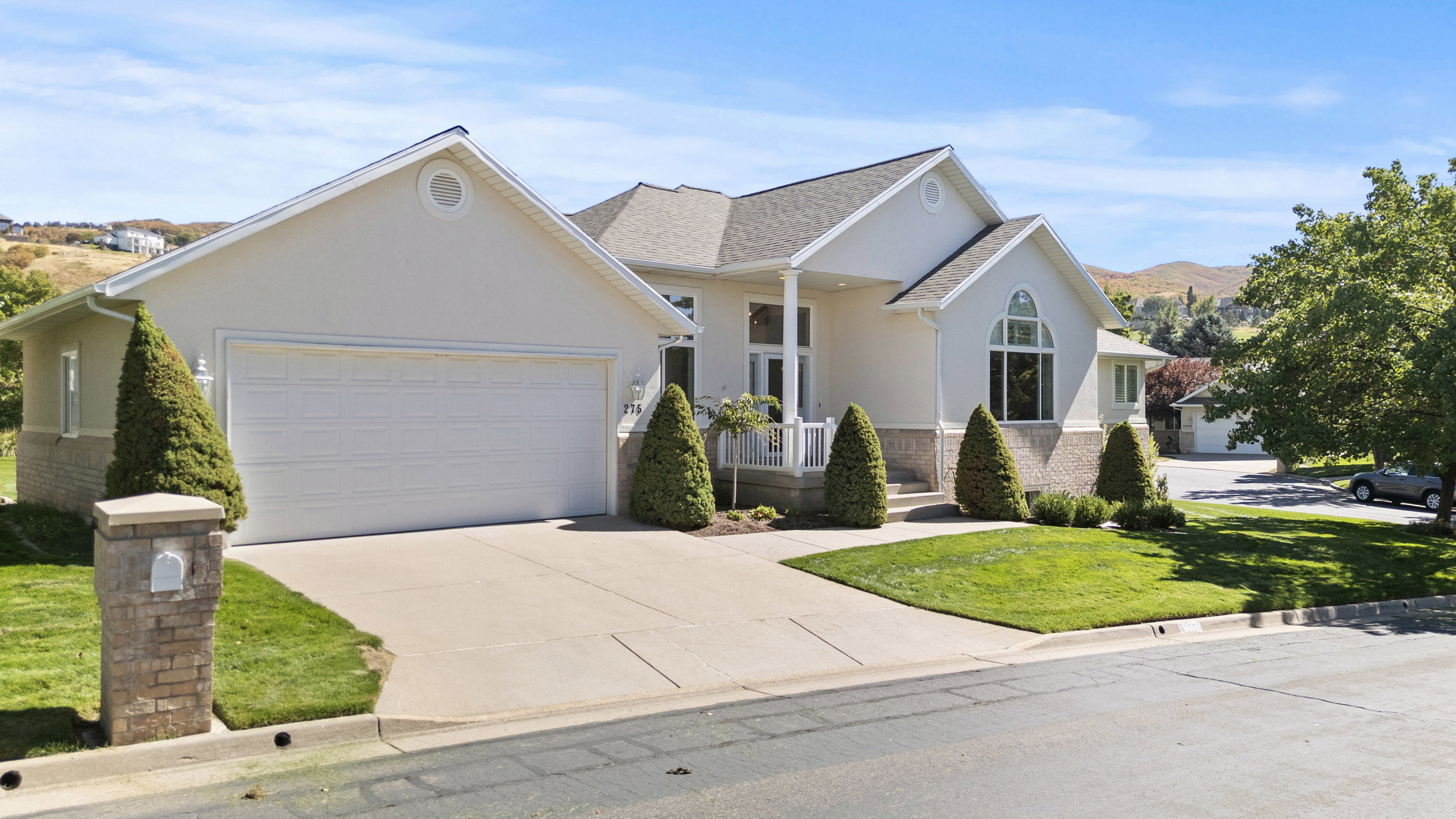 View of front of house featuring stucco siding, a porch, a garage, and driveway