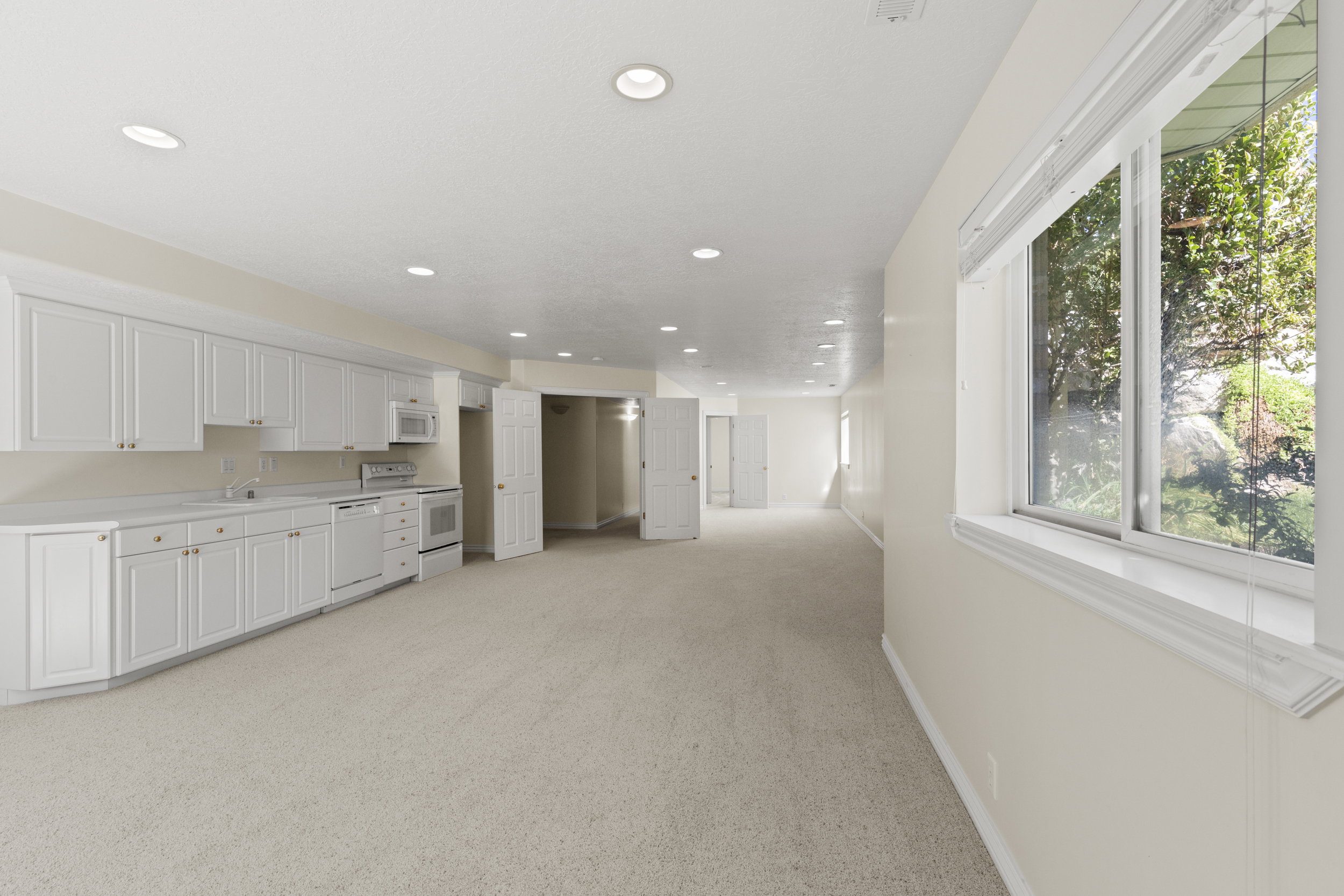 Kitchen featuring light countertops, light colored carpet, white appliances, white cabinets, and recessed lighting