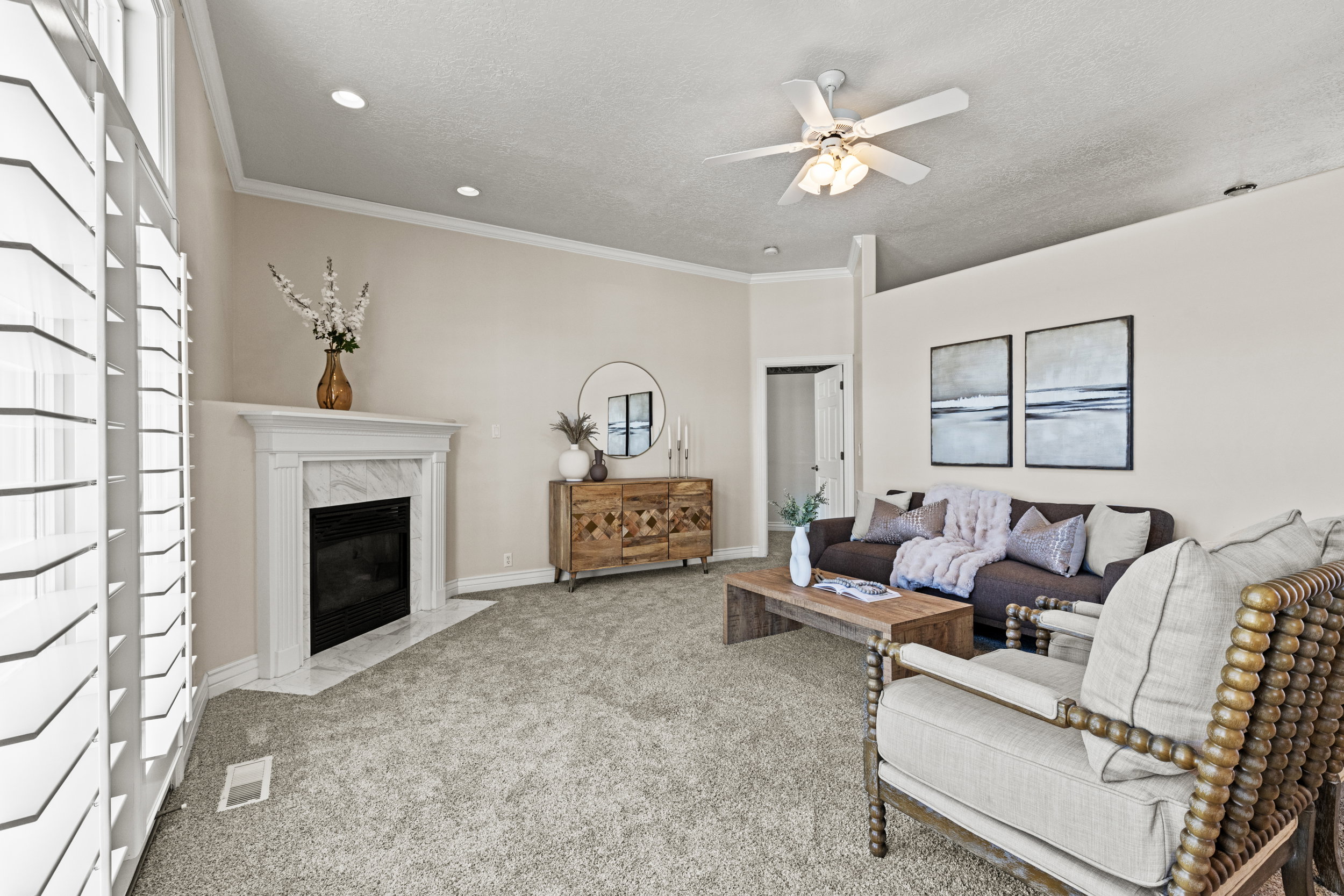 Living room featuring carpet flooring, a fireplace, ceiling fan, crown molding, and a textured ceiling