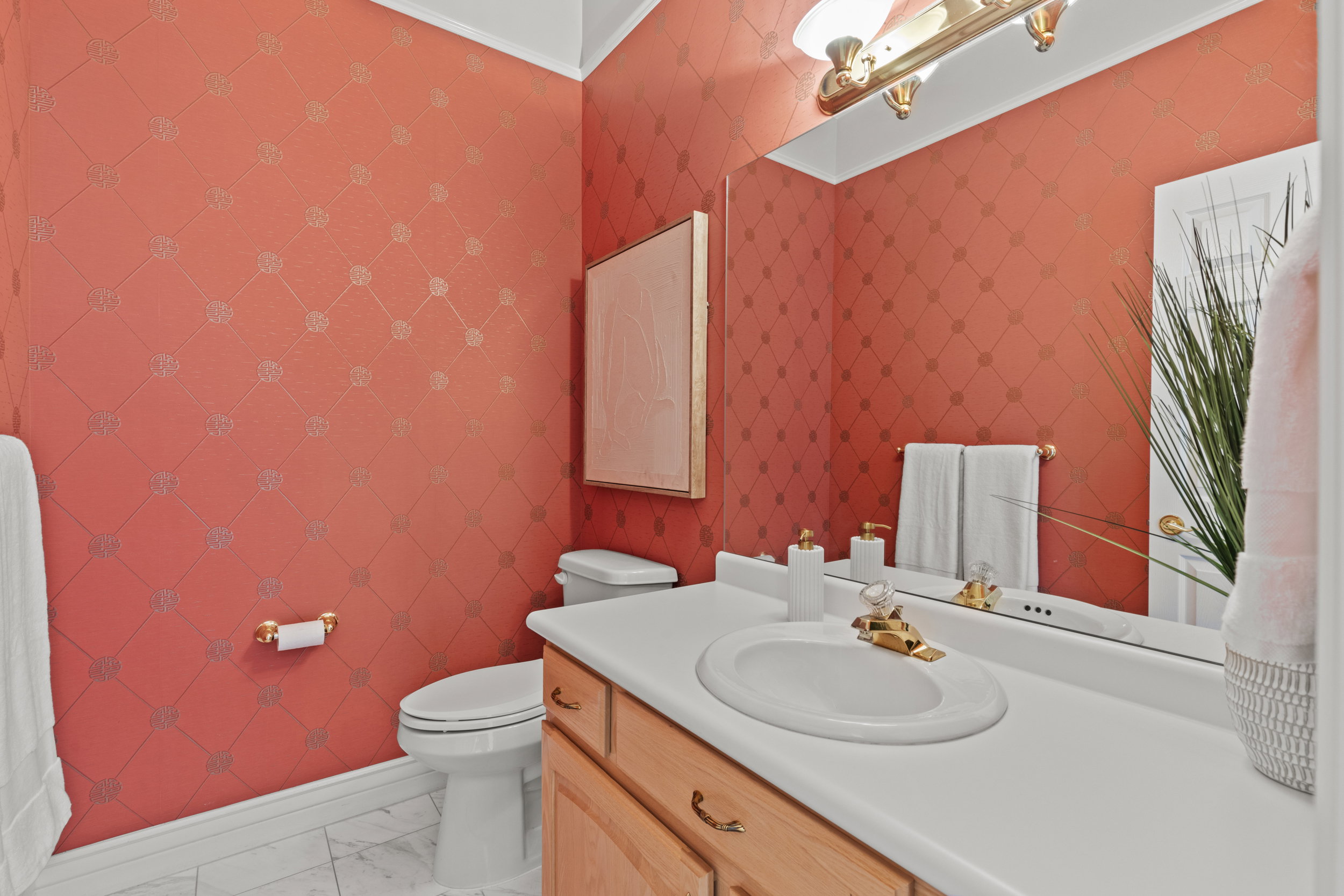 Half bath with vanity, light marble finish floors, and wallpapered walls