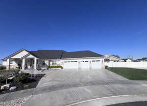 View of front facade featuring stone siding, an attached garage, covered porch, and driveway