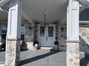 View of exterior entry featuring stone siding and a porch