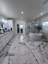 Bathroom featuring vanity, a marble finish shower, french doors, a soaking tub, and healthy amount of natural light