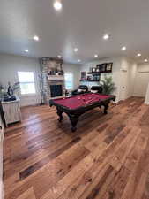 Recreation room with hardwood / wood-style flooring, billiards, a fireplace, a textured ceiling, and recessed lighting