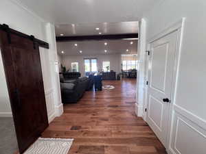 Corridor featuring a barn door, ornamental molding, dark wood-style floors, recessed lighting, and a textured ceiling