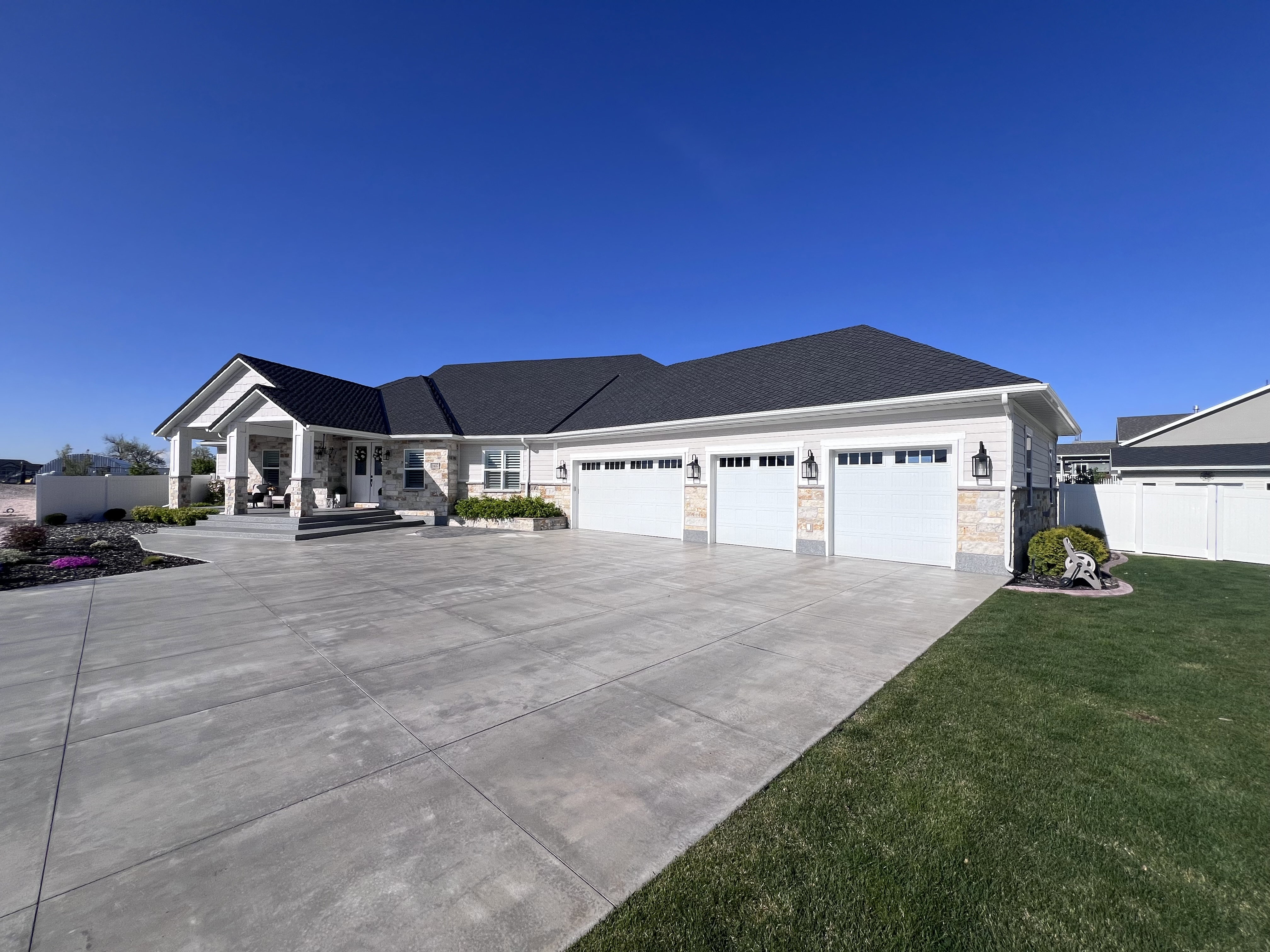 Ranch-style home with stone siding, an attached garage, driveway, and roof with shingles