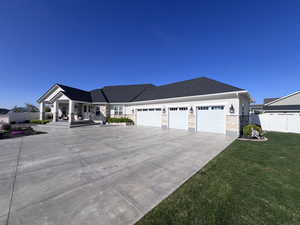 Ranch-style home with stone siding, an attached garage, driveway, and roof with shingles