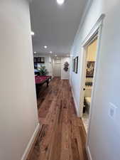 Hall featuring dark wood-type flooring, crown molding, and recessed lighting