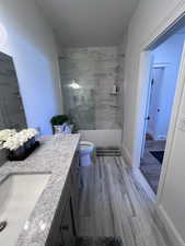 Bathroom with vanity, light wood finished floors, and combined bath / shower with glass door