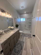 Bathroom featuring vanity, a stall shower, a textured ceiling, and light wood-type flooring