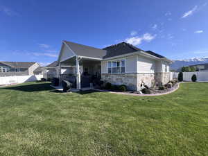 Rear view of house with a fenced backyard, stone siding, a patio area, and a mountain view