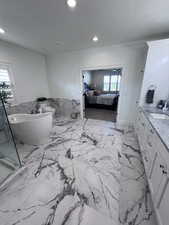 Bathroom featuring vanity, a wainscoted wall, connected bathroom, a soaking tub, and recessed lighting