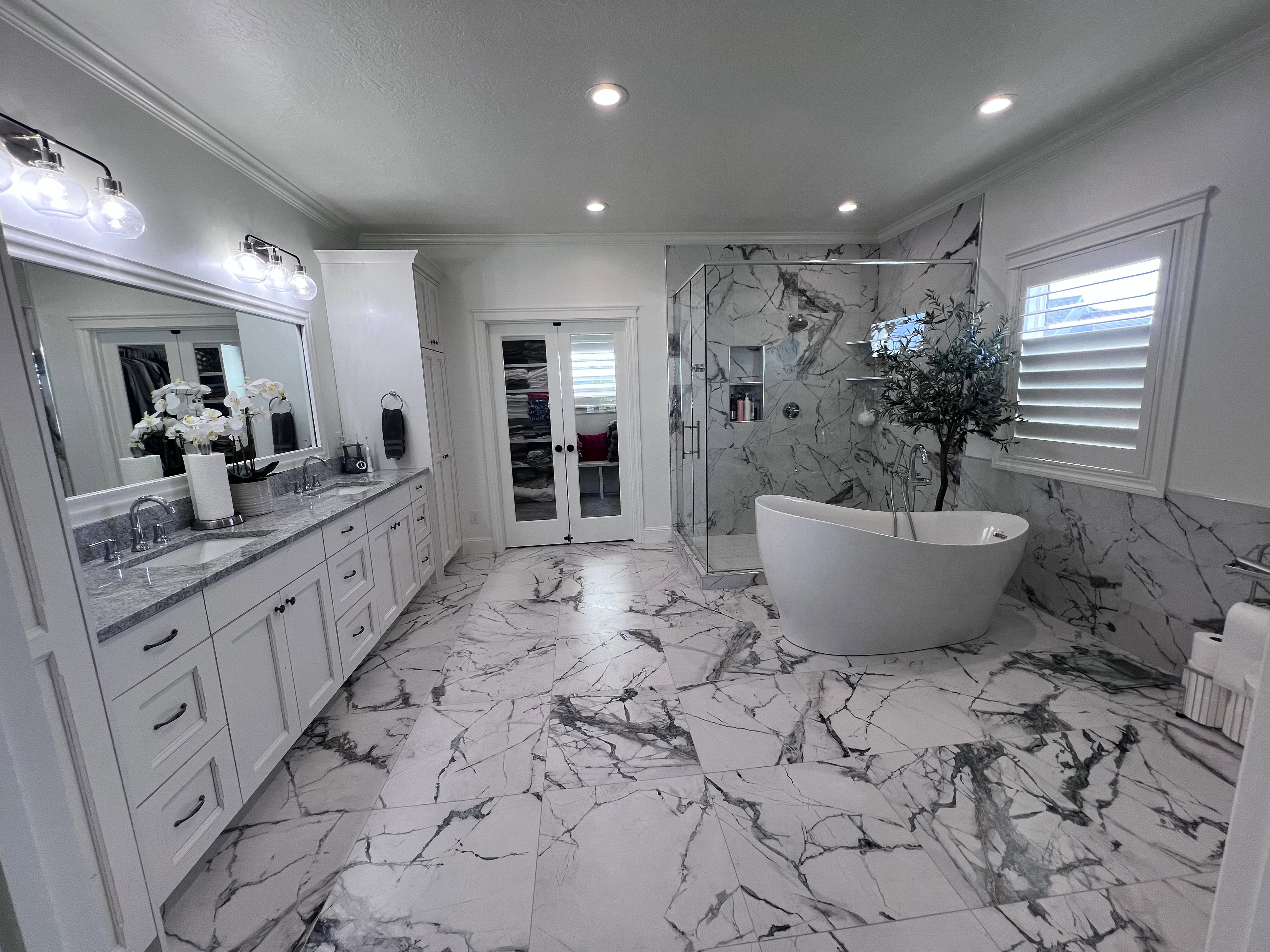 Full bath featuring double vanity, a marble finish shower, recessed lighting, french doors, and a freestanding tub