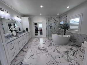 Full bath featuring double vanity, a marble finish shower, recessed lighting, french doors, and a freestanding tub
