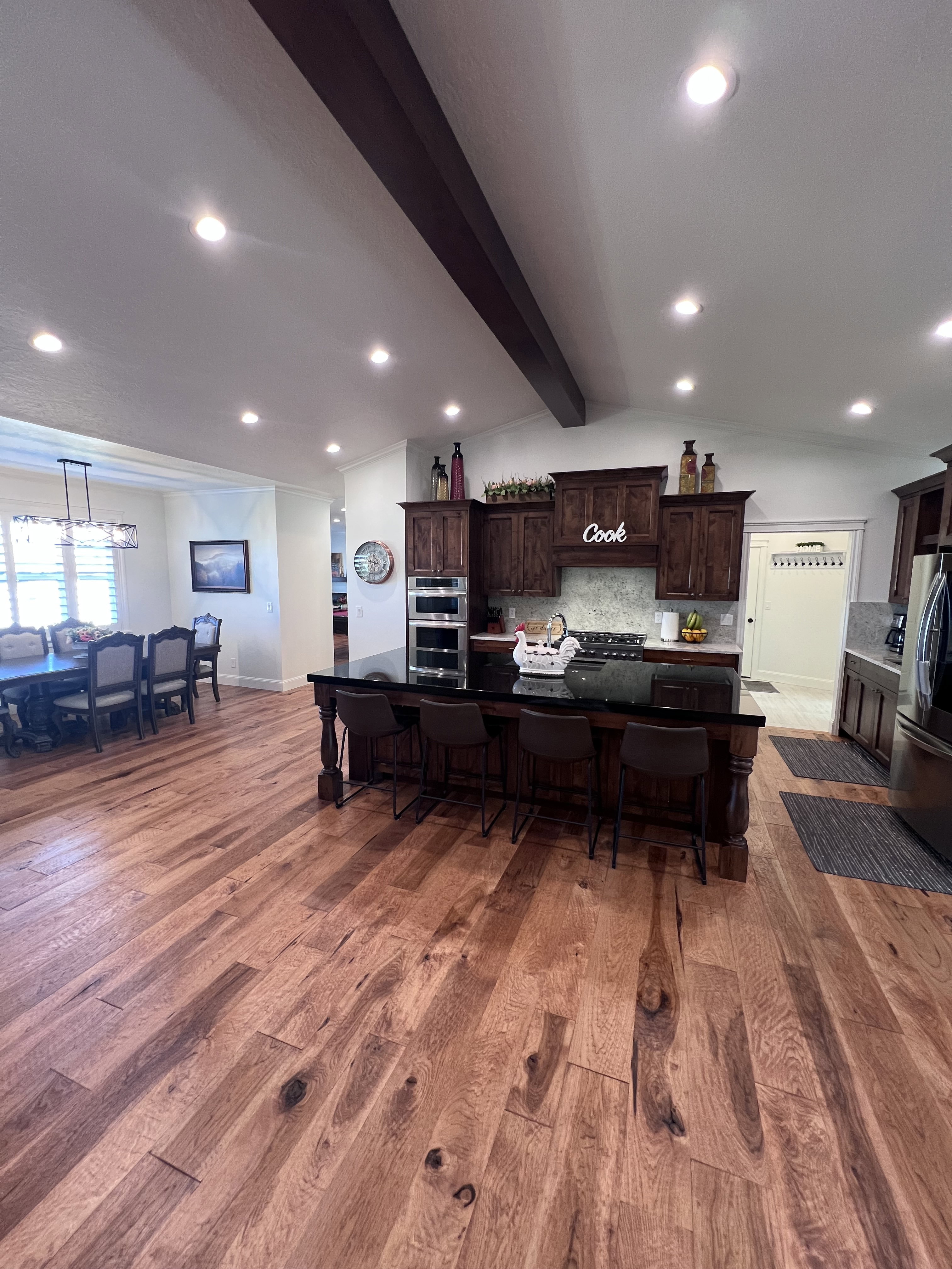 Kitchen featuring a breakfast bar area, a large island with sink, dark wood finish cabinetry, backsplash, and stainless steel appliances