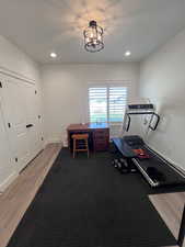 Exercise area with light wood-style flooring and suspended lighting
