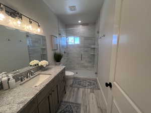 Bathroom featuring a shower stall, vanity, a textured ceiling, and light wood finished floors