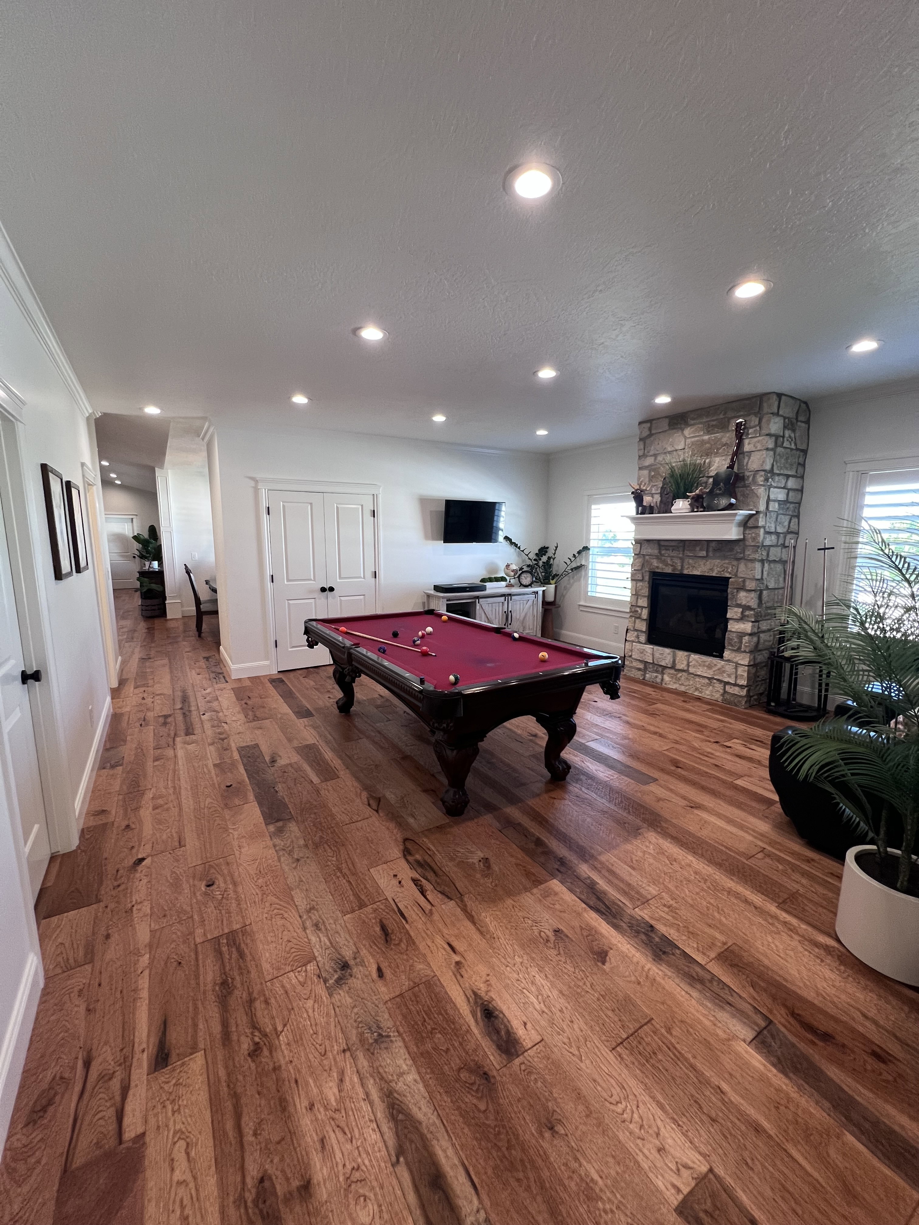 Game room with a textured ceiling, hardwood / wood-style floors, pool table, recessed lighting, and a stone fireplace