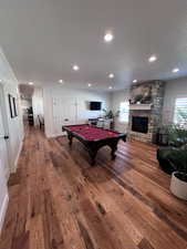 Game room with a textured ceiling, hardwood / wood-style floors, pool table, recessed lighting, and a stone fireplace