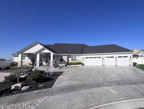 View of front of property featuring stone siding, covered porch, a garage, and driveway