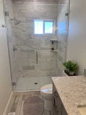 Full bathroom featuring vanity, a shower stall, and light wood-style flooring