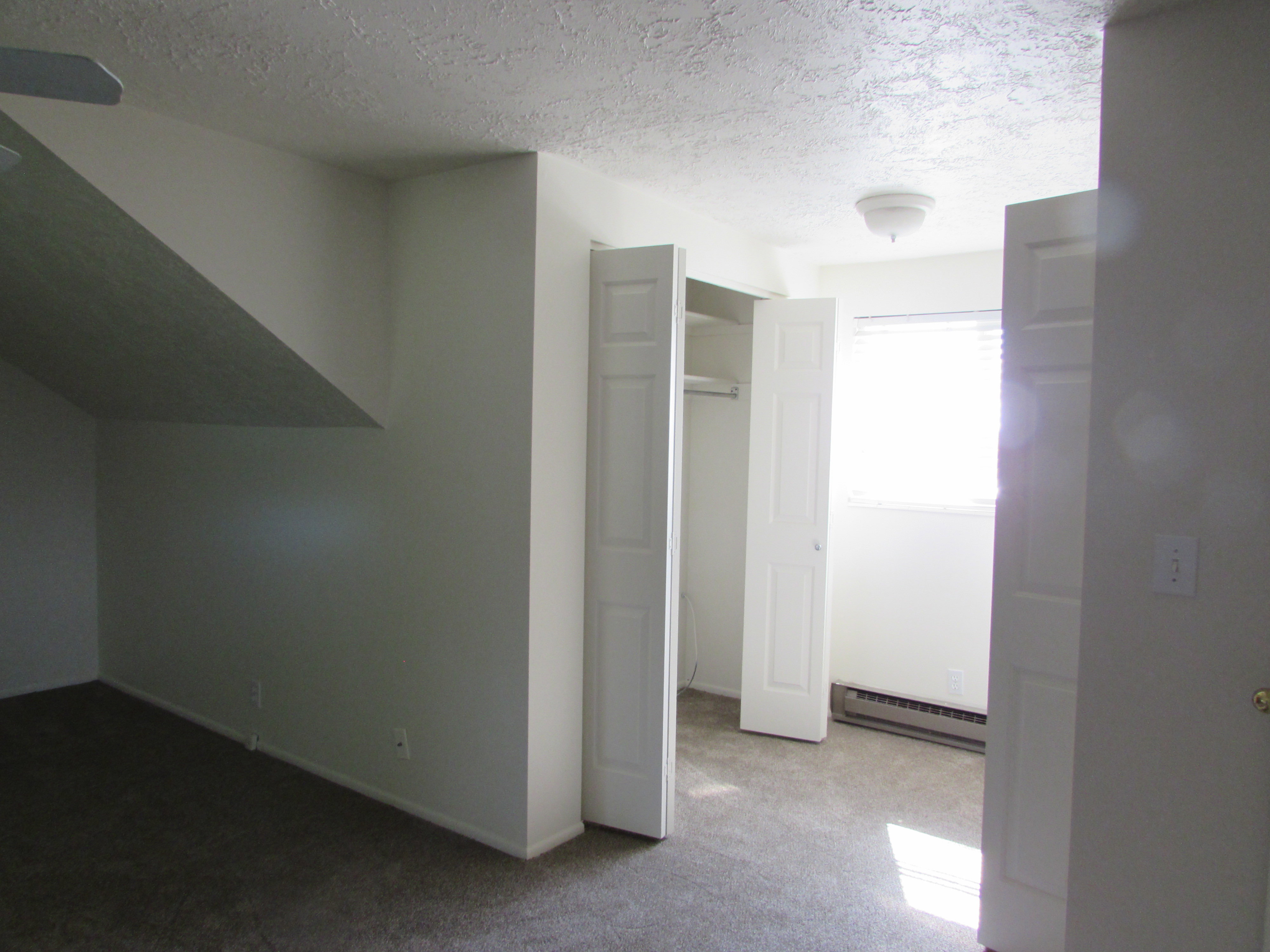 Unfurnished bedroom featuring light colored carpet, baseboard heating, a textured ceiling, and a closet