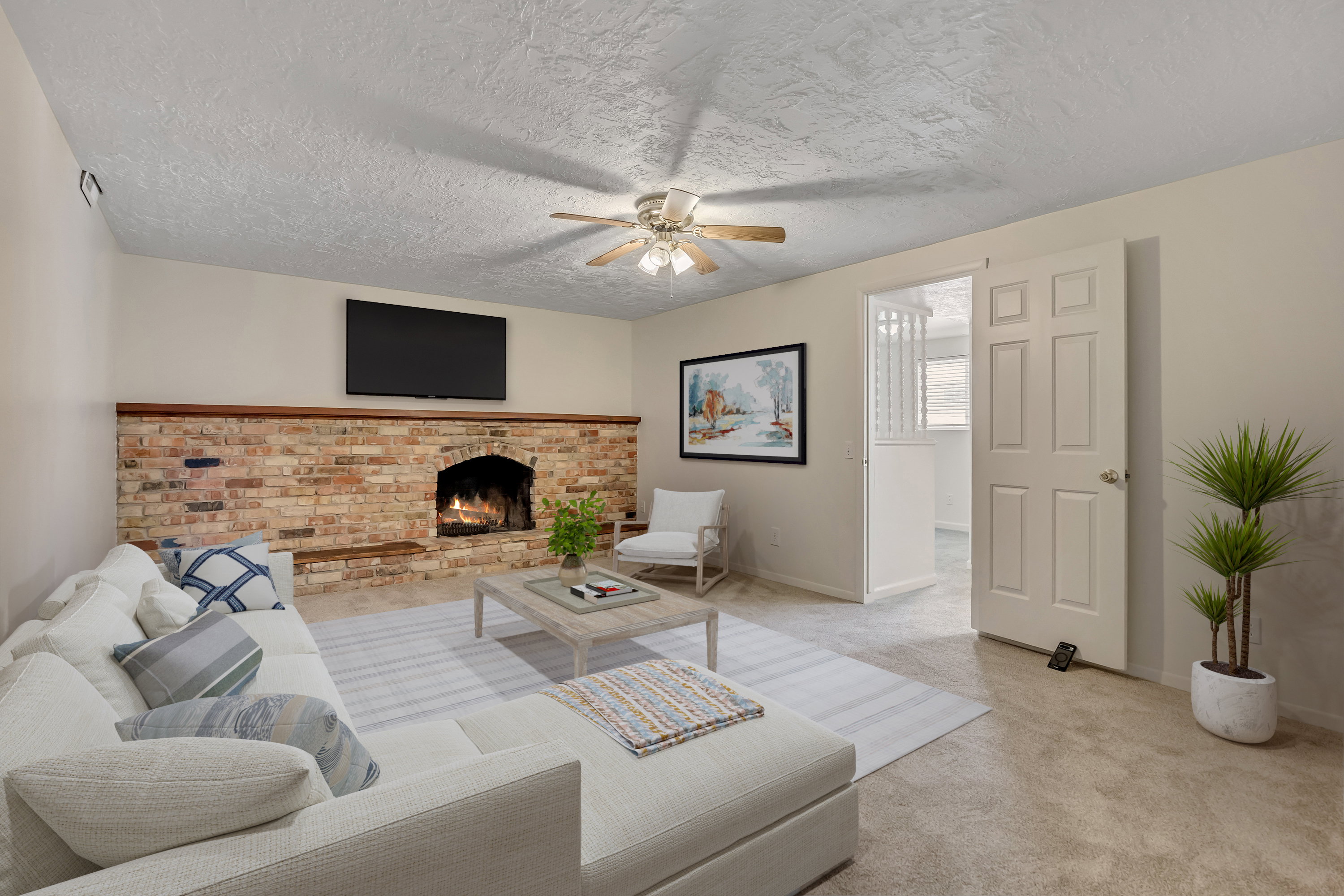 Family room featuring carpet, ceiling fan, a brick fireplace, and a textured ceiling (virtually staged)