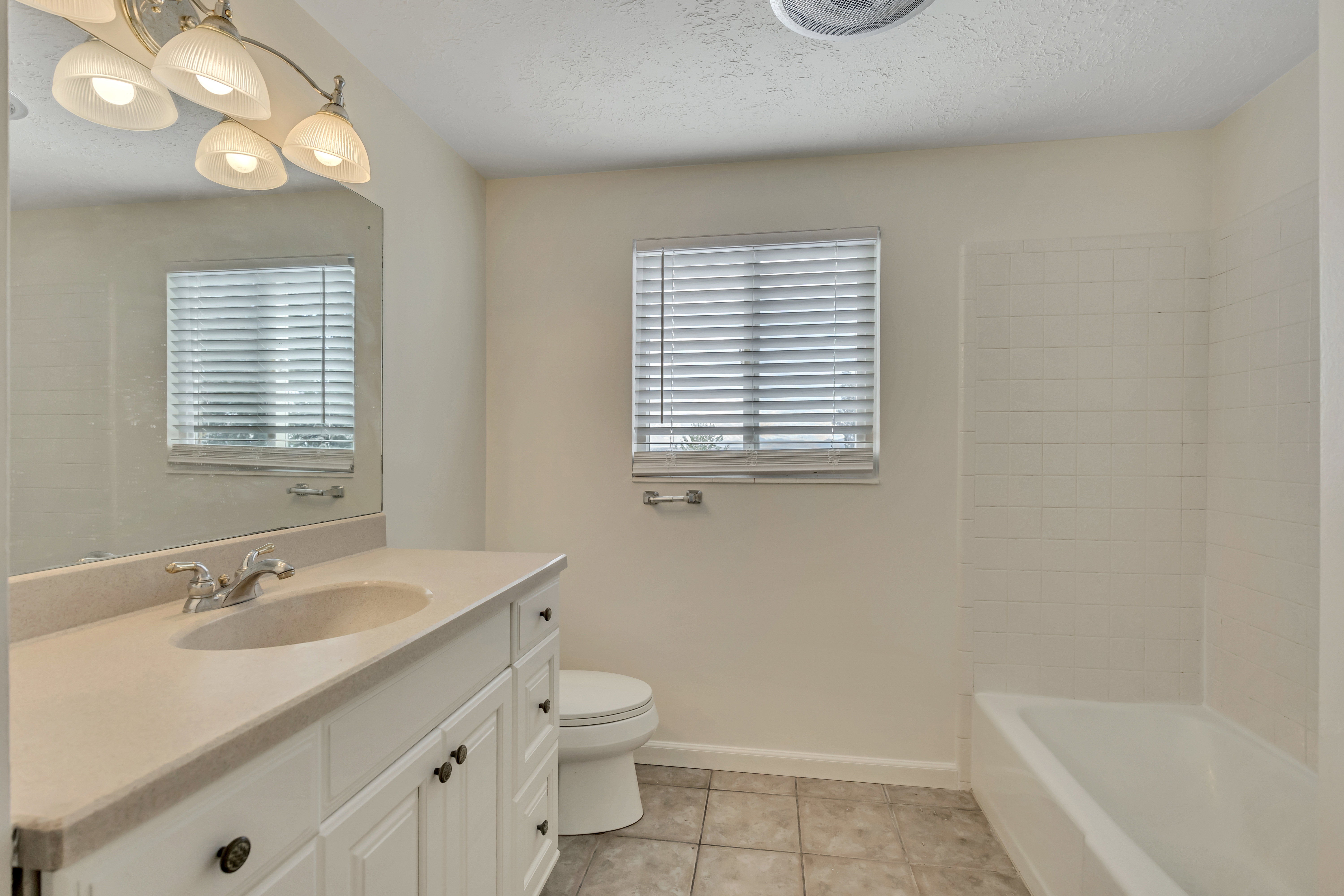 Bathroom with vanity, light tile patterned floors, healthy amount of natural light, and a textured ceiling