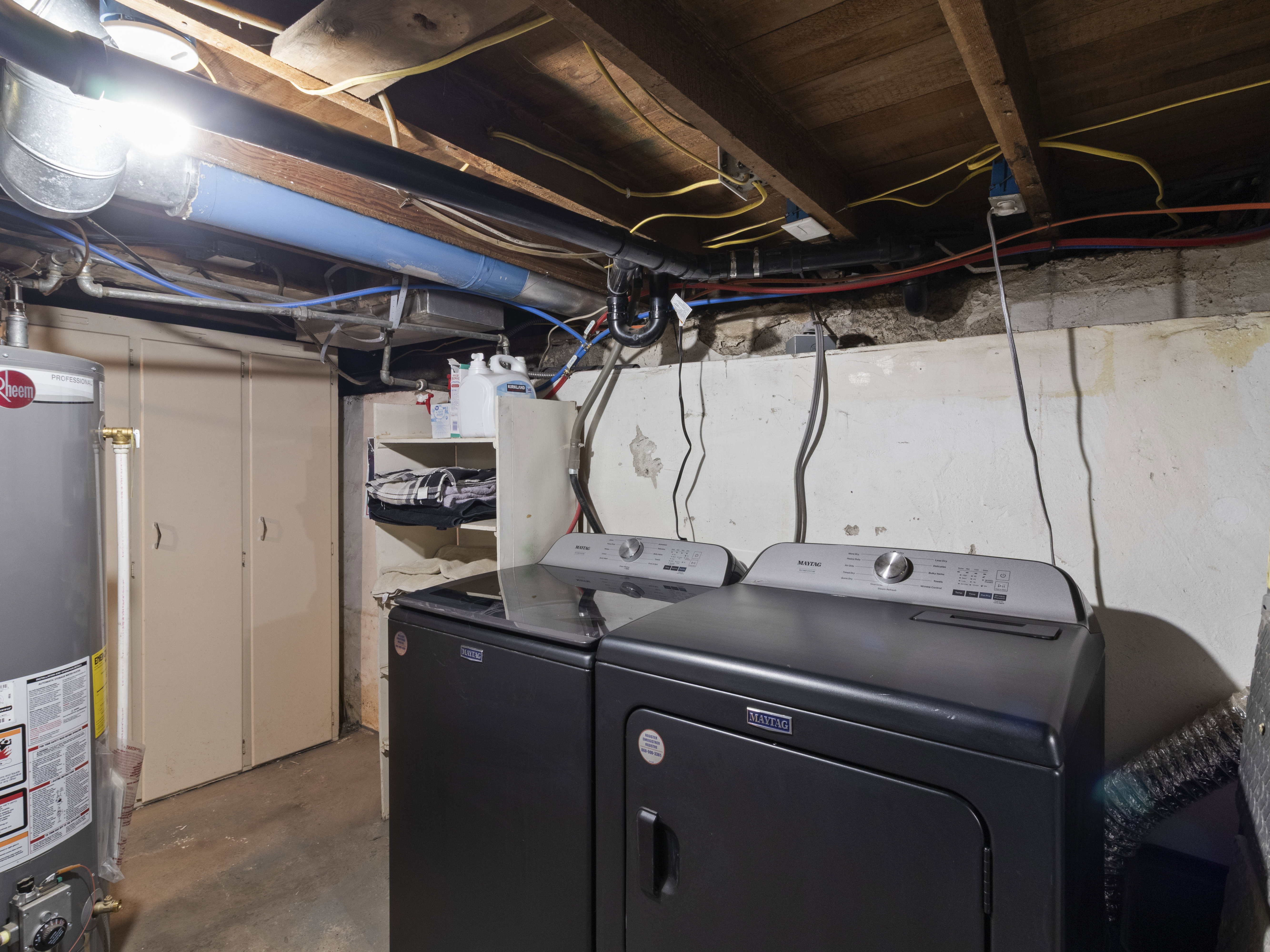 Laundry area featuring concrete flooring, water heater, and washing machine and clothes dryer