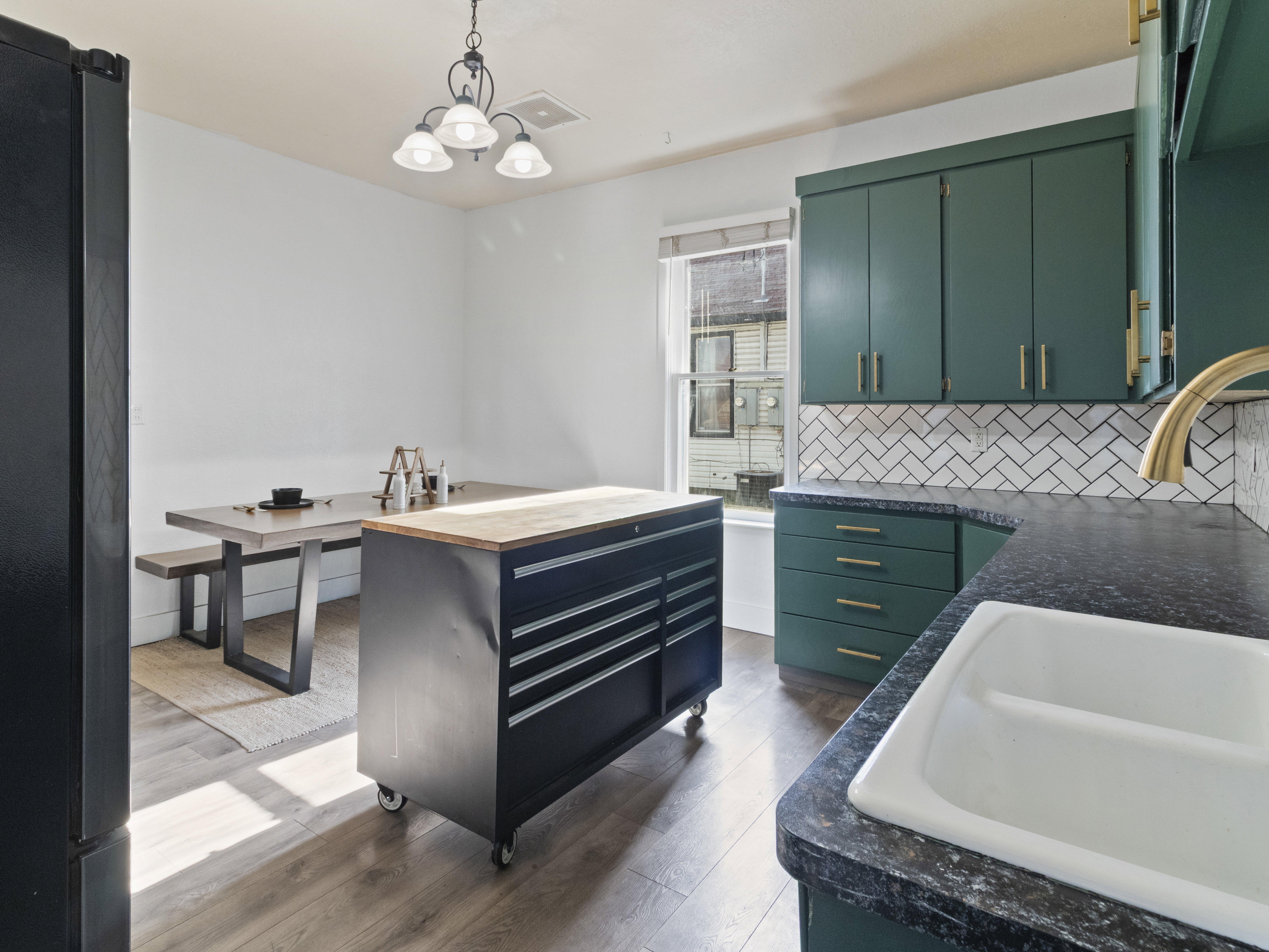 Kitchen featuring freestanding refrigerator, dark wood-style flooring, green cabinets, backsplash, and a chandelier