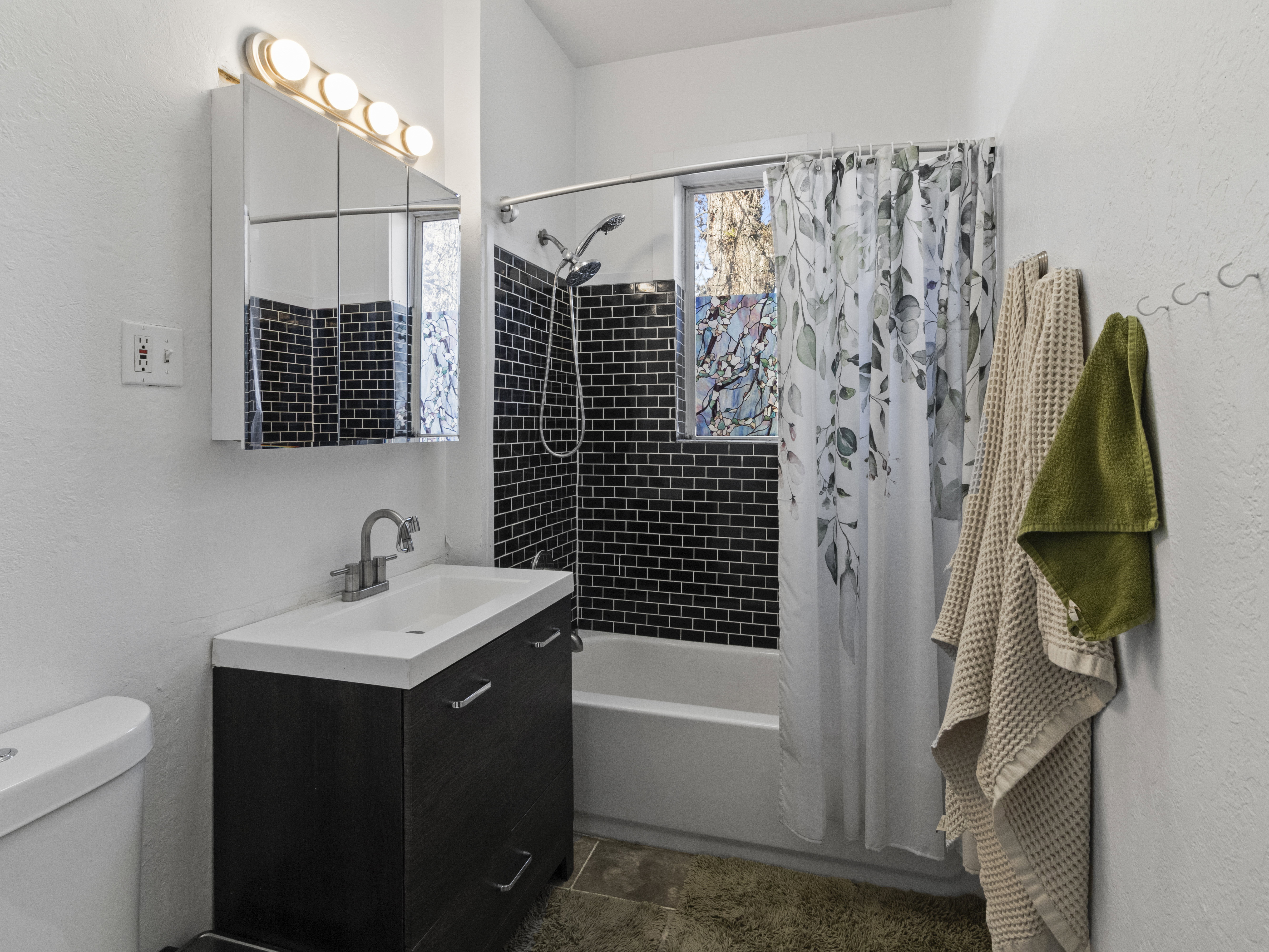 Bathroom featuring vanity, a textured wall, and shower / bath combination with curtain
