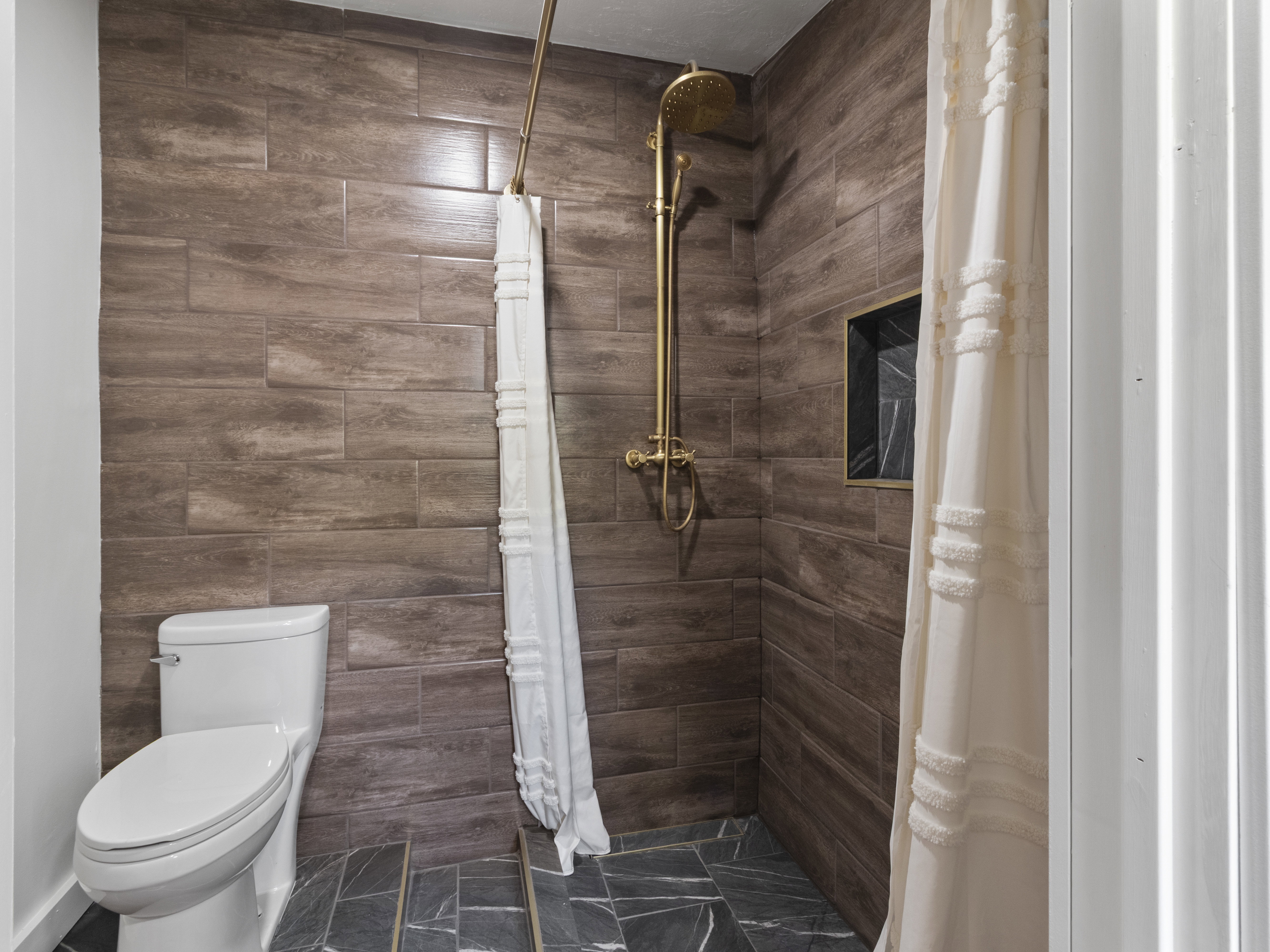 Bathroom with a shower stall and dark marble finish floors
