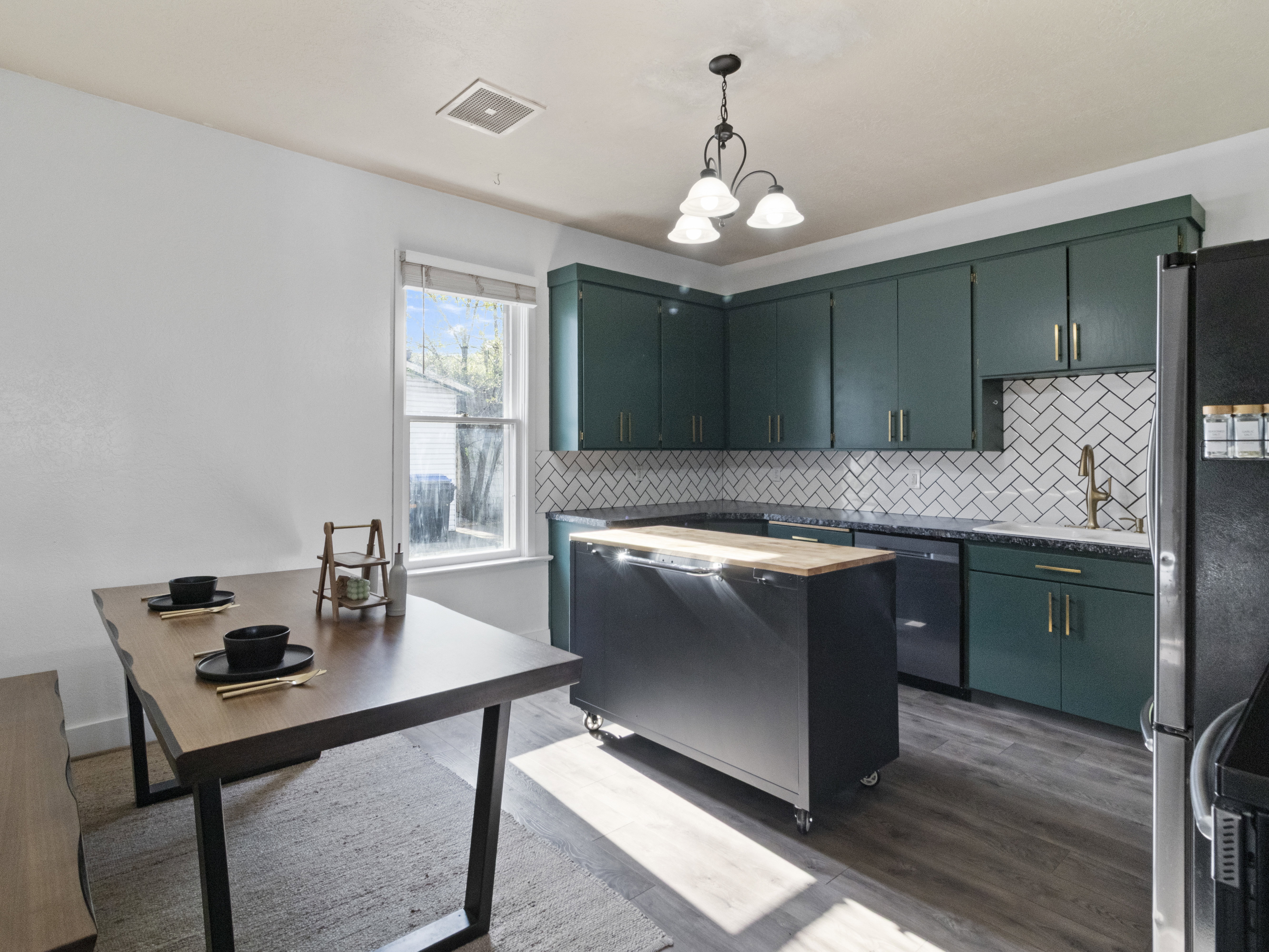 Kitchen with stainless steel appliances, tasteful backsplash, dark wood-style floors, green cabinets, and a chandelier