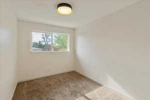 Spare room featuring light colored carpet and baseboards