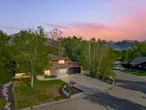 View of front of property featuring driveway, brick siding, a front lawn, and a mountain view