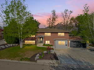 Raised ranch with a yard, brick siding, and concrete driveway