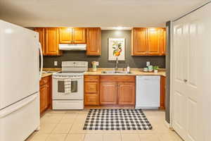 Kitchen with white appliances, wood finish cabinets, and light countertops