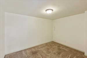 Carpeted spare room featuring baseboards