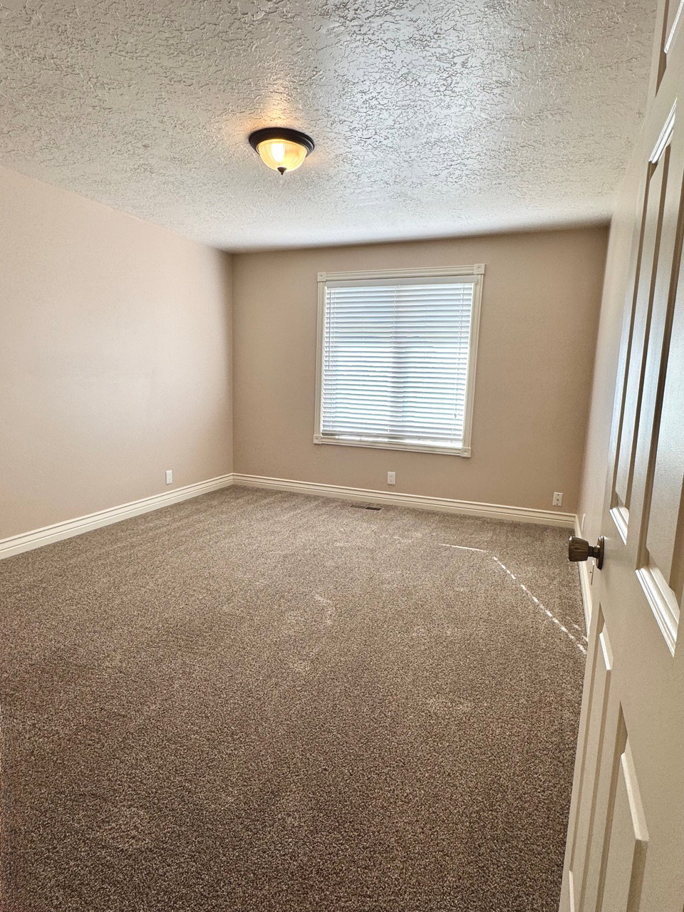 Carpeted room with a single window featuring horizontal blinds