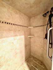 Walk-in shower featuring neutral-toned wall tiles with a decorative mosaic accent band