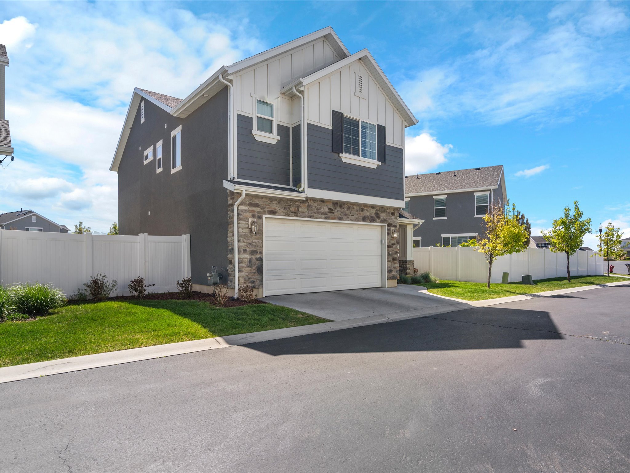 Craftsman-style home with stone siding, an attached garage, board and batten siding, and concrete driveway